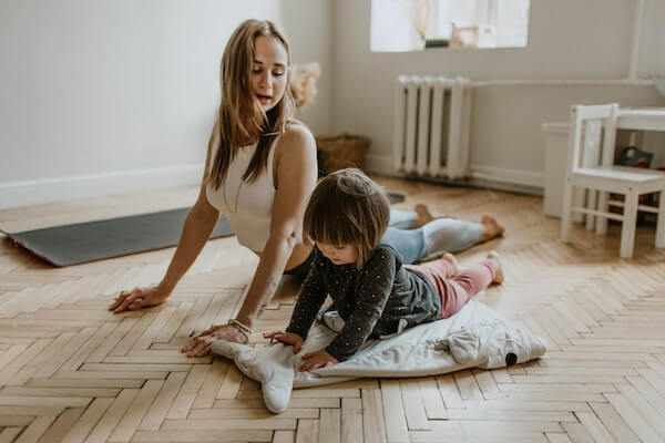Small child
doing yoga at home with her mother