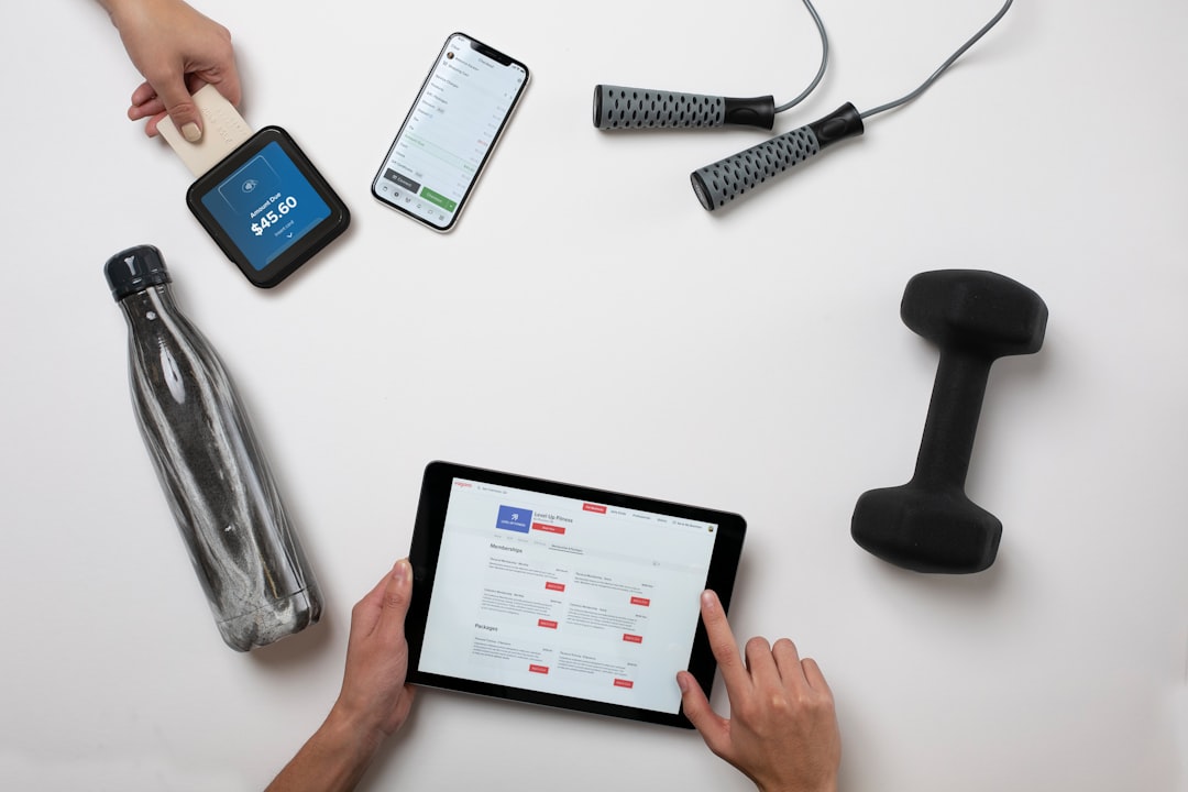 A smartphone and tablet beside a skipping rope, dumbbell and water bottle