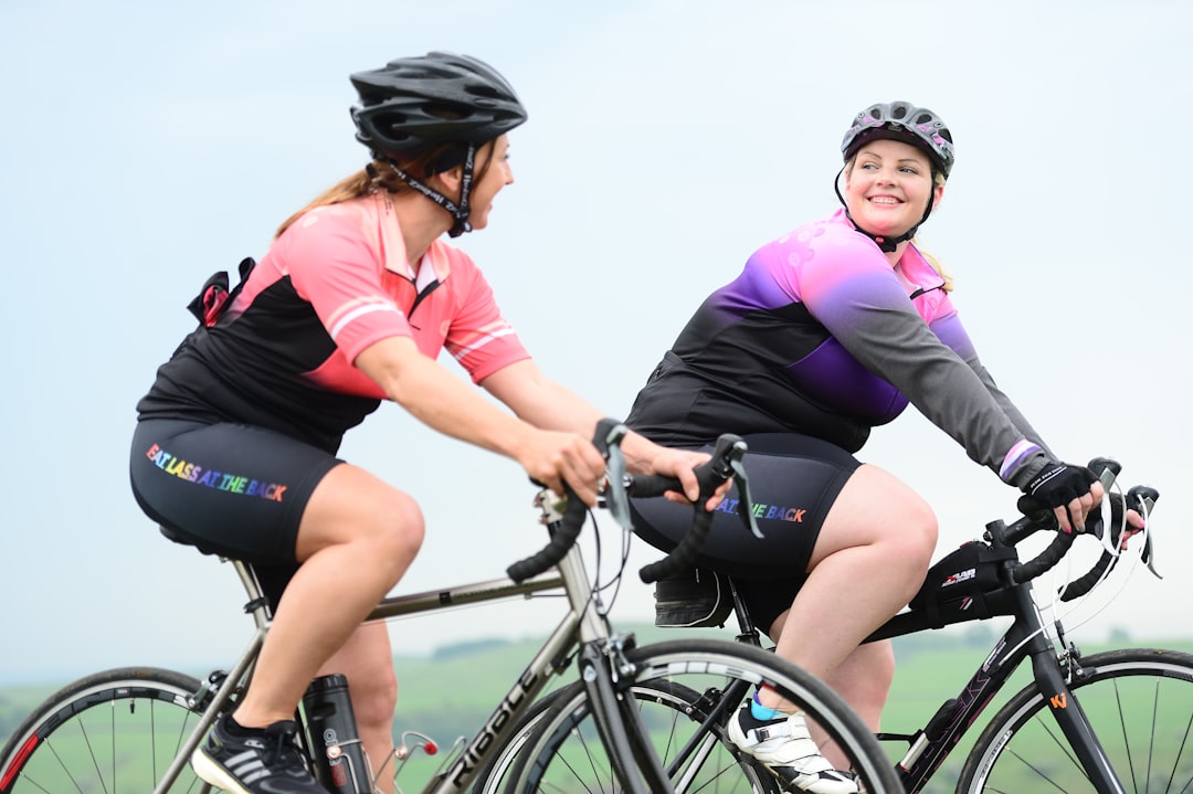 Two women smiling while riding road bikes together on a country lane