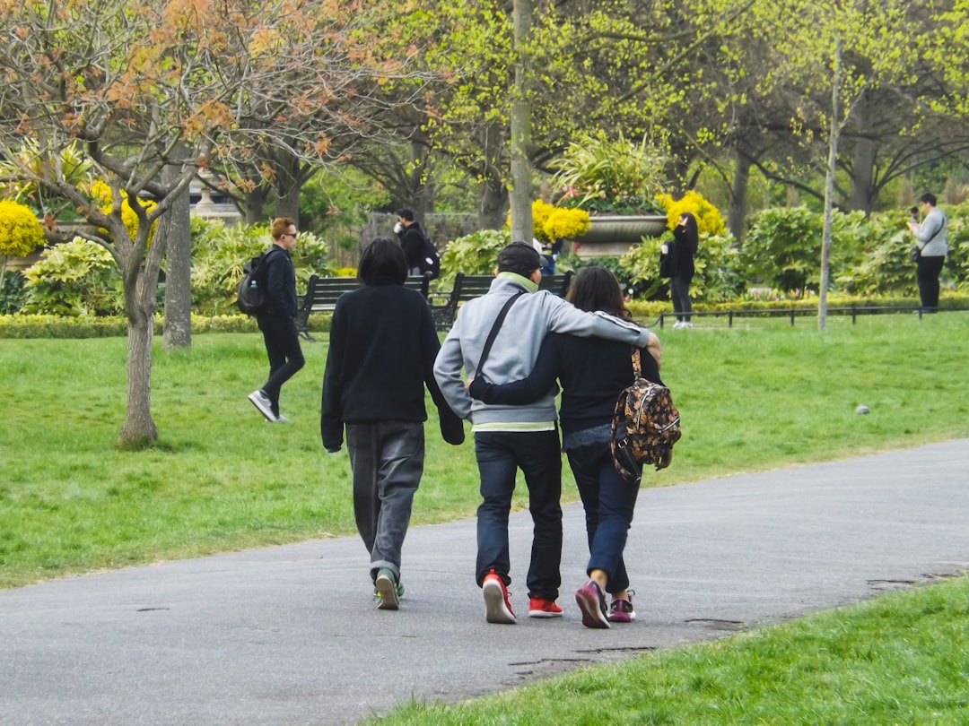 Three people walking together on a path through a park