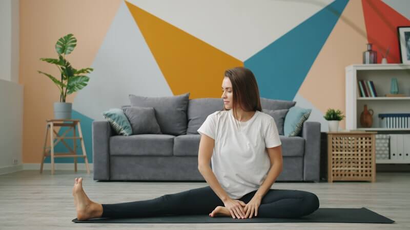 A woman stretching on a yoga mat in a living room