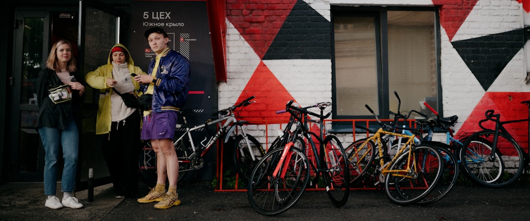 Three cyclists standing beside parked bikes outside a cafe