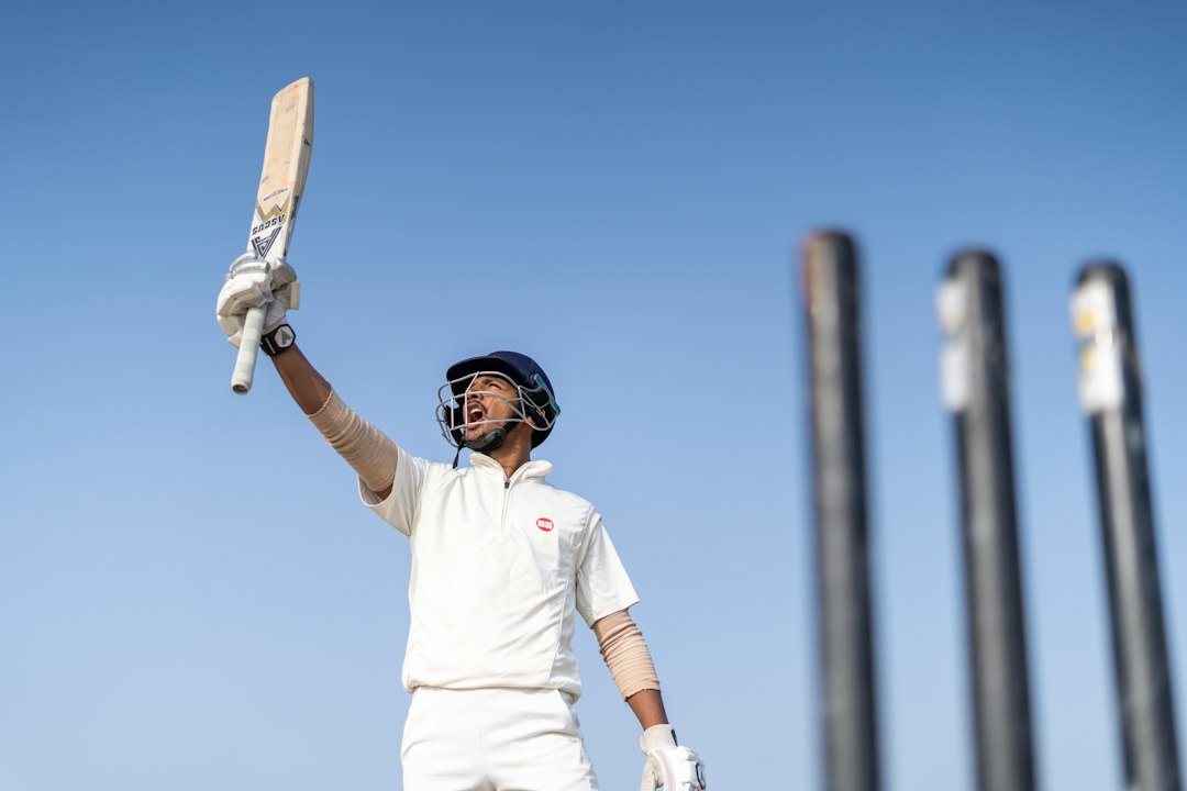 Cricketer wearing a helmet and holding a bat beside the stumps