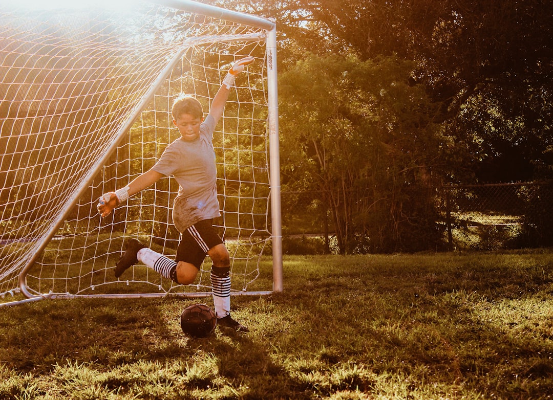 Young child at junior soccer training kicking a football