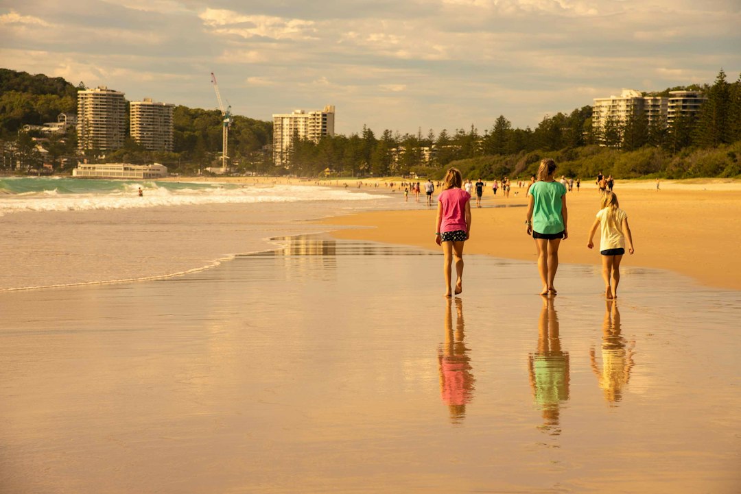 Three people walking along a Gold Coast beach at sunset
