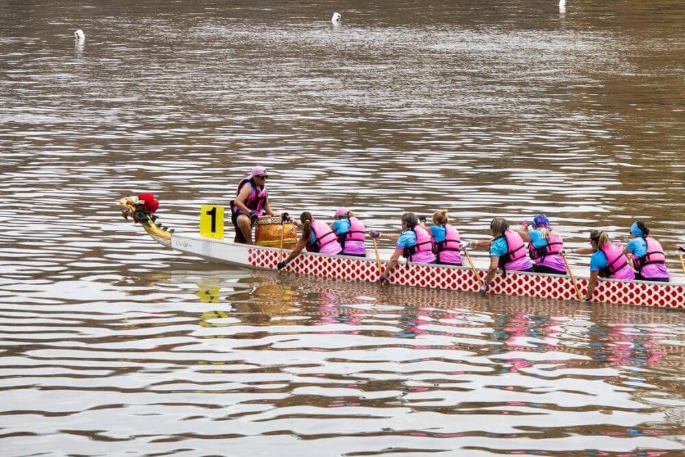 A dragon boat crew paddling together on calm water