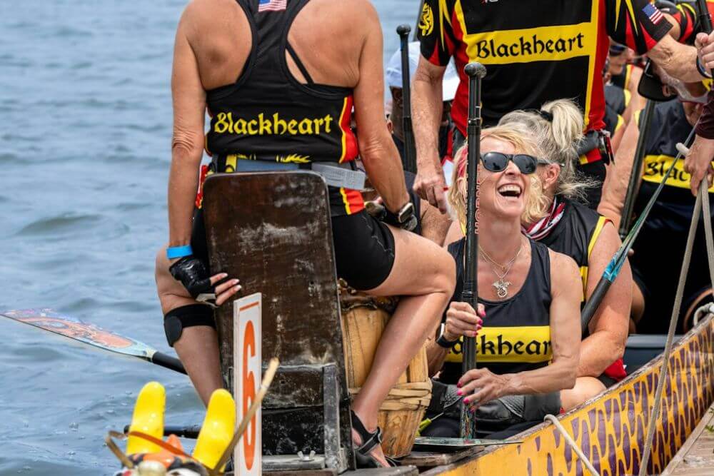 Dragon boat paddlers smiling together while seated in their boat
