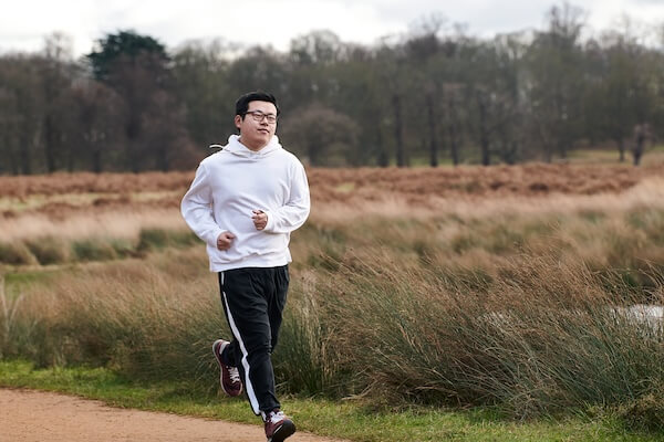 A man running outdoors outdoors along a lake path in Australia