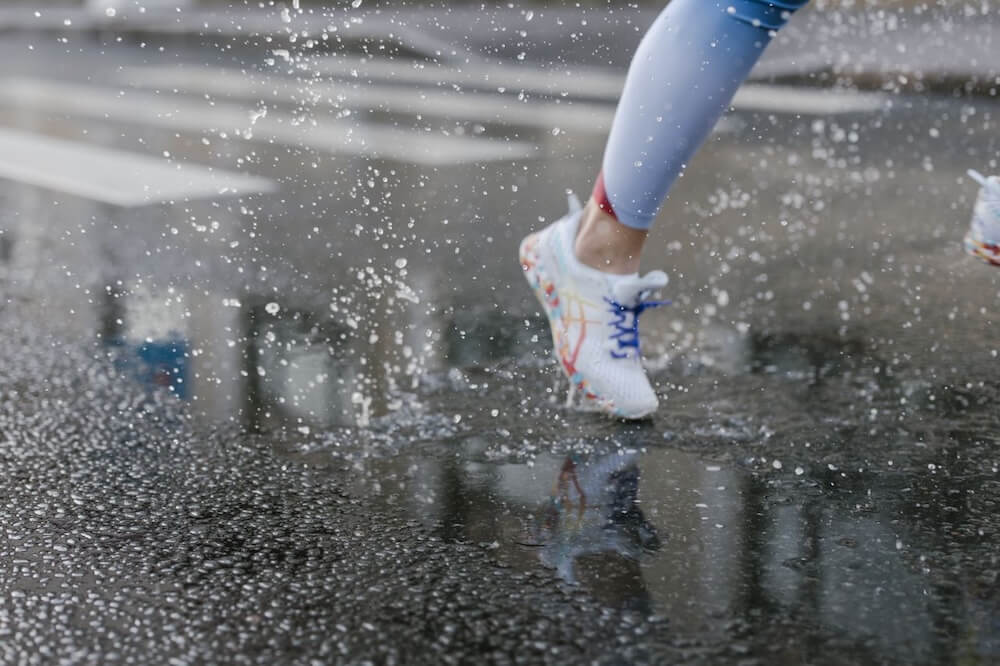 Running shoes splashing through a shallow puddle