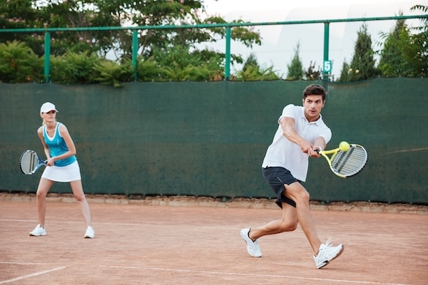 a
player returning a backhand shot with their doubles partner in
the background