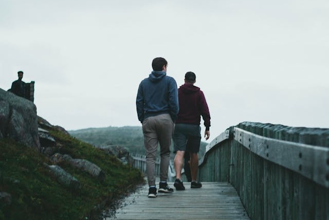 Two people walking on a path by a beach