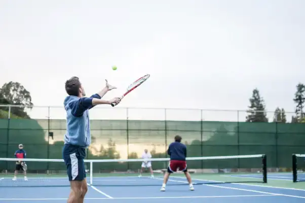 Man doing tennis serve during a doubles game